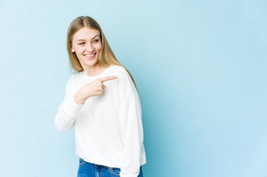 Mavi arka planda soyutlanmış genç sarışın kadın. Gülümsüyor, neşeli ve hoş görünüyor..