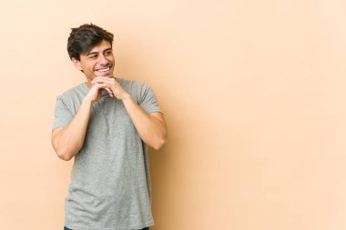 Genç havalı adam ellerini çenesinin altında tutuyor, mutlu bir şekilde yan tarafa bakıyor..