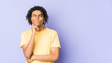 Genç Afrikalı Amerikalı Rasta adam şüpheli ve şüpheci bir ifadeyle yana bakıyor..