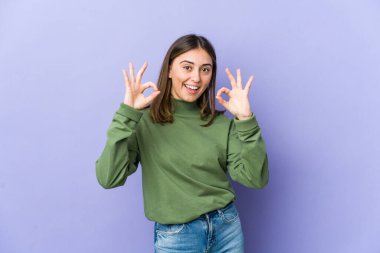 Genç, beyaz, neşeli ve kendinden emin bir kadın iyi bir jest yapıyor..