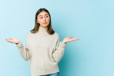 Kafası karışmış genç beyaz bir kadın, bir kopya alanı tutmak için omuz silkiyor..