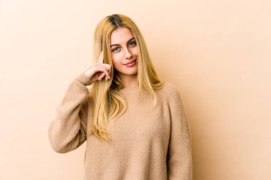 Sarışın, beyaz bir kadın şakağı parmağıyla işaret ediyor, düşünüyor ve bir göreve odaklanıyor..