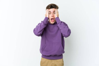 Beyaz arka planda izole edilmiş genç beyaz bir adam yüzünün yarısını palmiye ile örterek eğleniyor..