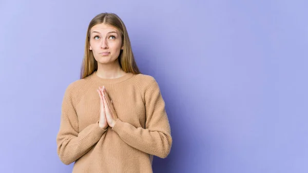 若いですブロンド女性孤立紫色の背景保持手で祈りで口の近く 自信を感じます — ストック写真