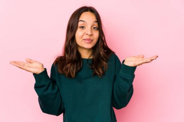 Latin kökenli genç bir kadın şüpheye düşüp omuz silkerek jestlerini sorguluyor..