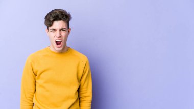 Mor arka planda izole edilmiş genç beyaz adam çok kızgın, öfkeli, hayal kırıklığına uğramış diye bağırıyor..