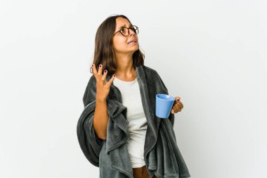 Beyaz arka planda battaniyeli genç Latin bir kadın gökyüzüne haykırıyor, bakıyor, hayal kırıklığına uğruyor..