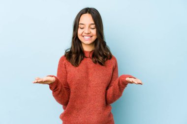 Latin kökenli genç bir kadın avuçlarıyla bir şey tutup kameraya sunuyor..