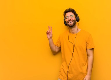 Genç adam müzik dinliyor, zafer jesti yapıyor.