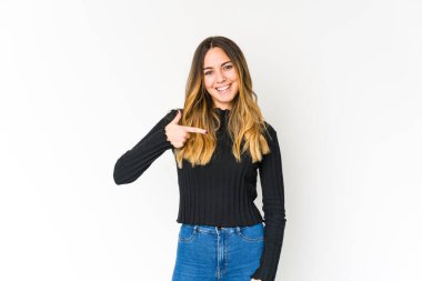 Beyaz arka planda yaşayan beyaz tenli genç bir kadın gömlek fotokopi alanını elle işaret ediyor, gururlu ve kendinden emin