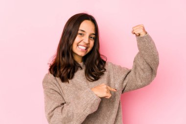 Genç, Latin kökenli bir kadın, kendini izole etmiş, parmaklarıyla küçük bir şey tutuyor, gülümsüyor ve kendinden emin..
