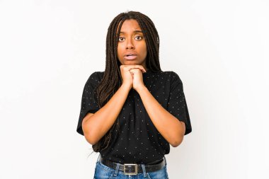 Genç Afrikalı Amerikalı kadın beyaz arka planda izole edilmiş şans için dua ediyor, şaşırıyor ve ağzını açıyor..