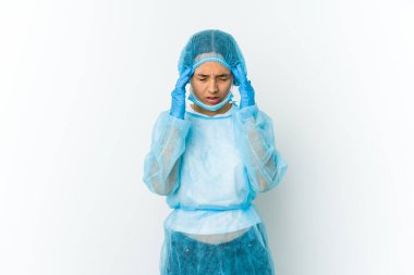 Beyaz arka planda izole edilmiş genç bir cerrah, tapınaklara dokunuyor ve baş ağrısı çekiyor..