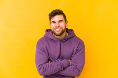 Sarı arka planda izole genç beyaz adam gülüyor ve eğleniyor..