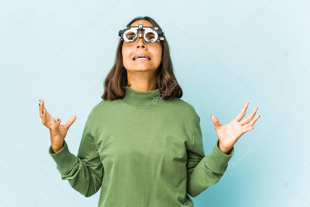 Young oculist latin woman over isolated background screaming to the sky, looking up, frustrated.
