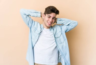 Beyazlı genç bir adam bej arka planda izole edilmiş, kollarını uzatmış, rahat bir konumda..