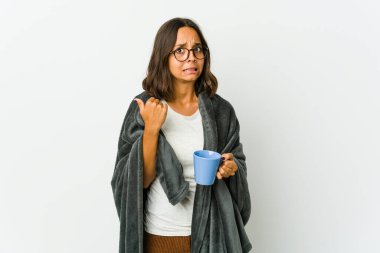 Beyaz arka planda battaniyeli genç Latin kadın işaret parmağıyla fotokopi alanını işaret ederek şok oldu..