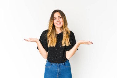 Beyaz arka planda izole edilmiş genç beyaz bir kadın. Kafası karışmış ve omuz silkiyor. Kopya alanını tutmak için..