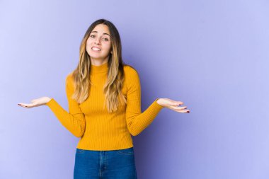 Mor arka planda soyutlanmış beyaz bir kadın. Kafası karışmış ve omuz silkiyor. Kopya alanını tutmak için..