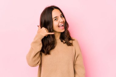 Genç melez İspanyol kadın izole edilmiş, parmaklarıyla bir cep telefonu hareketi gösteriyor..