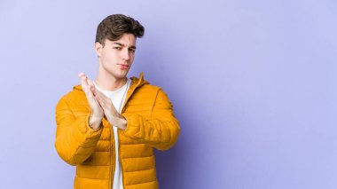 Mor arka planda izole olmuş genç beyaz adam enerjik ve rahat hissediyor, ellerini ovuşturuyor..