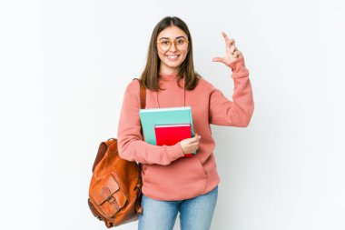 Beyaz fırında izole edilmiş genç bir kadın. Elinde işaret parmaklarıyla küçük bir şey tutuyor, gülümsüyor ve kendinden emin..