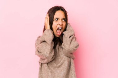 Genç, melez, İspanyol bir kadın. Kulaklarını ellerinle kapatıyor. Gürültülü sesler duymamaya çalışıyor..