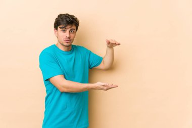 Genç havalı adam iki eliyle bir şey tutuyor, ürün sunumu..