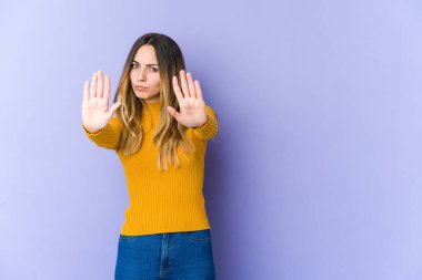 Mor arka planda izole edilmiş genç beyaz kadın elini uzatmış, dur işareti göstererek seni engelliyor..