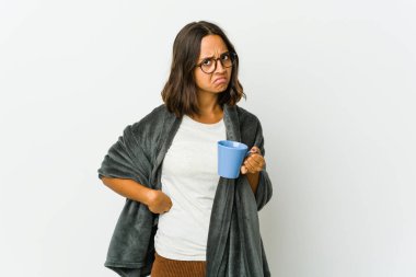 Beyaz arka planda battaniyeli genç Latin kadın kafası karışmış, şüpheli ve emin değil..