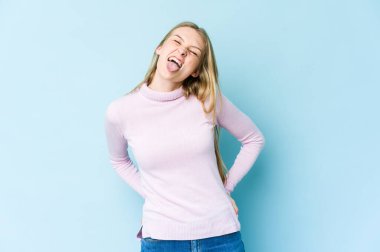 Mavi arka planda izole edilmiş genç sarışın kadın. Komik ve arkadaş canlısı, dilini dışarı çıkaran..