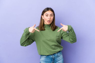 Genç beyaz kadın parmaklarıyla aşağı işaret ediyor, pozitif duygu..