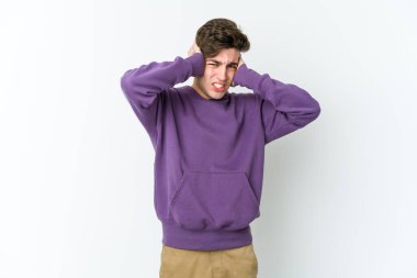 Beyaz arka planda izole edilmiş genç beyaz bir adam kulaklarını elleriyle kapatıyor..