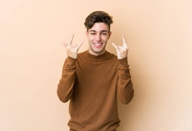 Beyazlı genç bir adam bej arka planda izole edilmiş boynuzlarını devrim konsepti olarak gösteriyor..