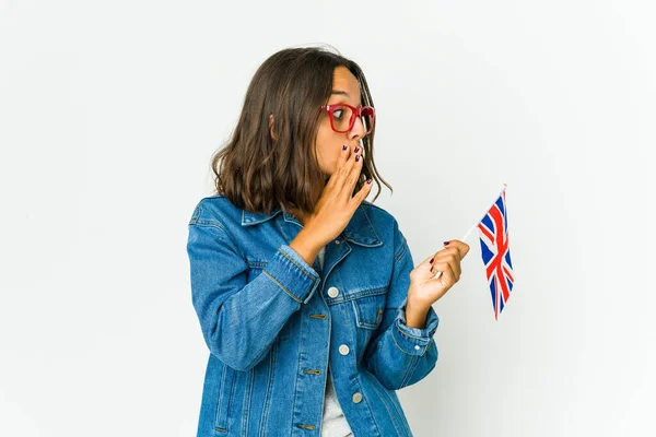 年轻的拉丁女子举着一面白色背景的英国国旗 正在说着一个秘密的 令人毛骨悚然的消息 并把目光投向了一旁 — 图库照片