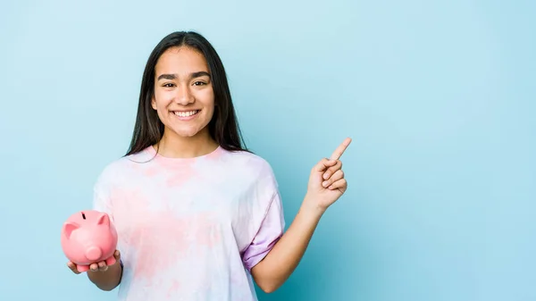 Joven Asiática Sosteniendo Banco Rosa Sobre Fondo Aislado Sonriendo Señalando — Foto de Stock