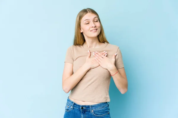 青い背景に隔離された若いブロンドの女性は 胸に手のひらを押して優しい表情をしています 愛の概念 — ストック写真