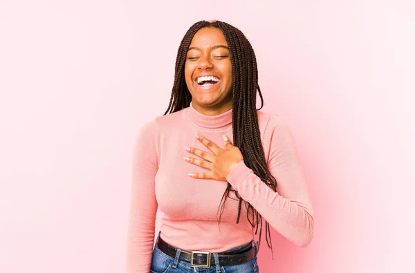 ピンクの背景に孤立した若いアフリカ系アメリカ人女性が大声で手を胸に保ち笑い — ストック写真