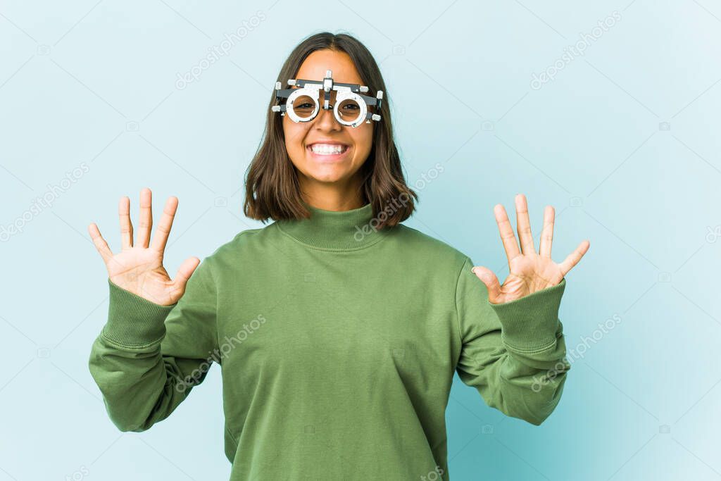Young oculist latin woman over isolated background showing number ten with hands.