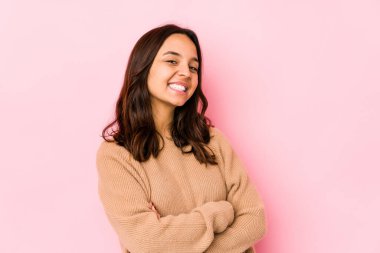 Genç, melez İspanyol kadın kendini soyutlamış, kollarını kavuşturarak gülümsüyor..