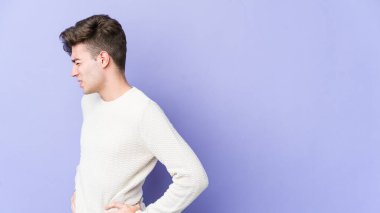 Mor arka planda izole edilmiş beyaz bir adam sırt ağrısı çekiyor..