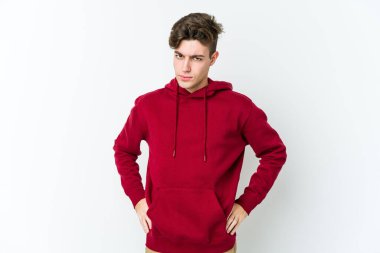 Beyaz arka planda izole edilmiş, hoşnutsuzca kaşlarını çatmış, kollarını kavuşturmuş genç beyaz bir adam..