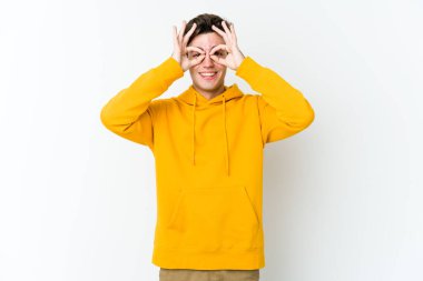 Beyaz arka planda izole edilmiş genç beyaz bir adam gözlerinde sorun olmadığını gösteriyor.