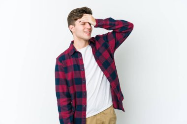 Beyaz arka planda izole olmuş genç beyaz bir adam ellerini başının üstünde tutarak neşeyle gülüyor. Mutluluk kavramı.