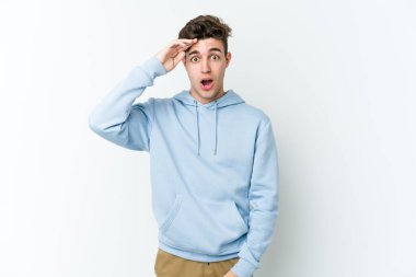 Beyaz arka planda izole genç beyaz adam yüksek sesle bağırıyor, gözleri açık ve elleri gergin tutuyor..