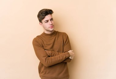 Beyazlı genç bir adam bej arka planda izole edilmiş amaçlarına ve amaçlarına ulaşmayı hayal ediyor.