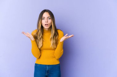 Mor arka planda izole genç beyaz kadın şaşırdı ve şok oldu..