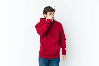 Genç havalı adam kameraya parmaklarıyla göz kırpıyor, utanarak yüzünü kapatıyor..