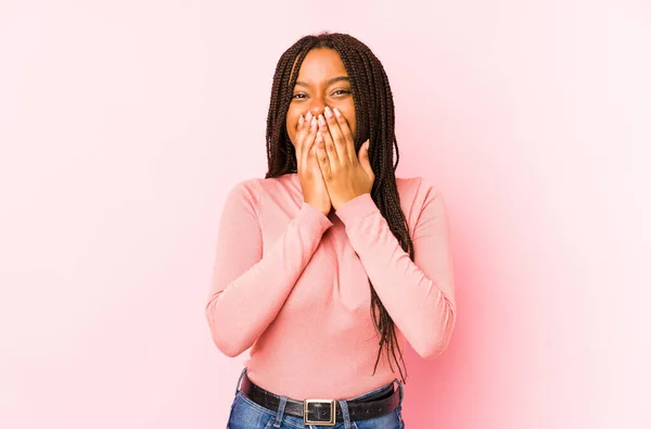 ピンクの背景に孤立した若いアフリカ系アメリカ人女性が何かを笑いながら口を手で覆い — ストック写真