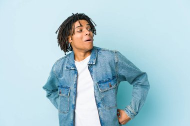 Kot ceket giyen genç siyah adam gülümseyen, neşeli ve keyifli bir kenara bakar..